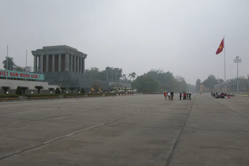 The wide paved expanse of Ba Dinh Square, with the grey stone Ho Chi Minh Mausoleum on the left and the national flag on a tall pole