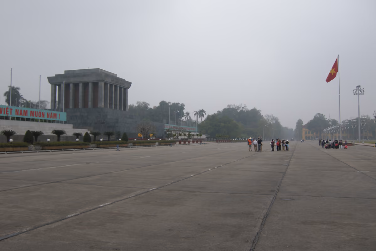 The wide paved expanse of Ba Dinh Square, with the grey stone Ho Chi Minh Mausoleum on the left and the national flag on a tall pole