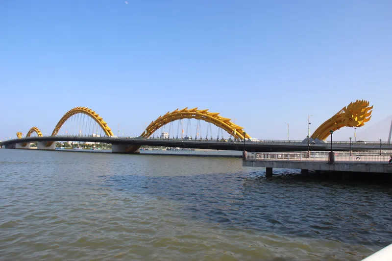 The Dragon Bridge, a long road bridge with yellow steel arches shaped like a dragon’s body, crossing the wide Han River under a clear blue sky
