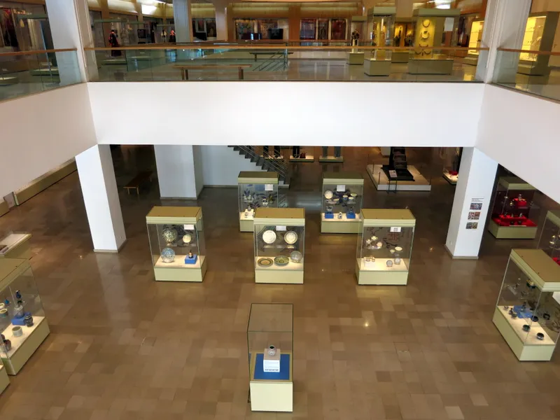 An atrium seen from an upper floor, with glass cases of ceramics on the lower gallery floor