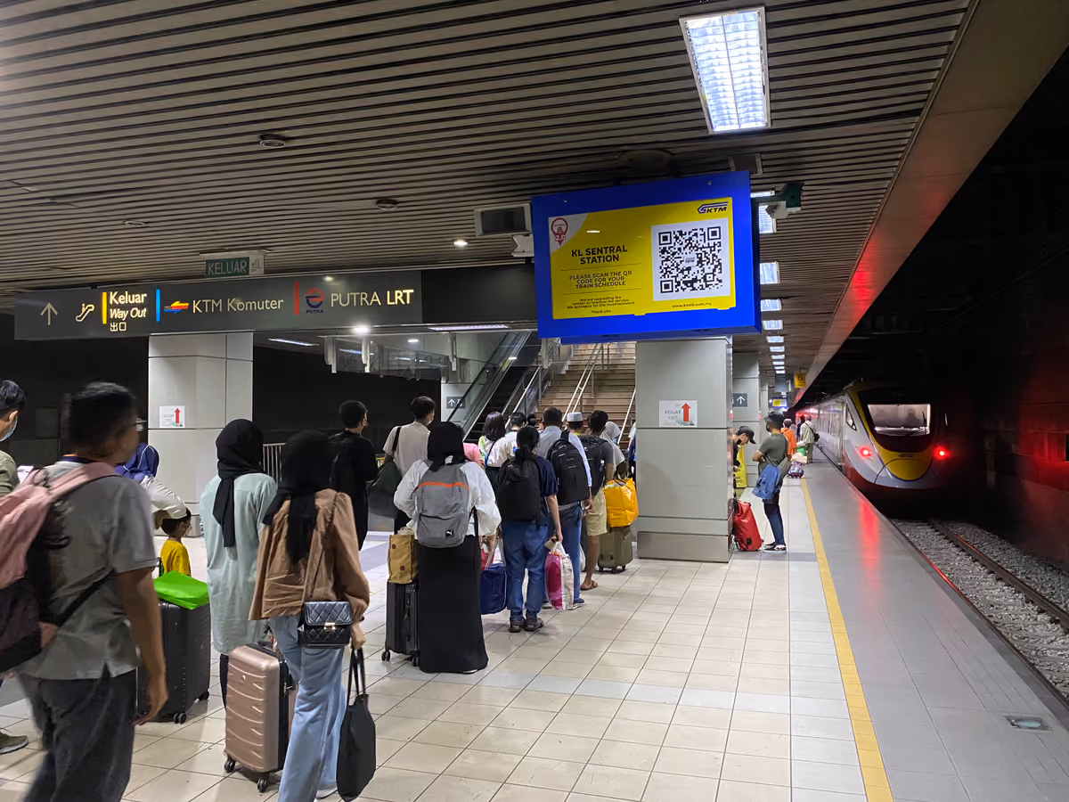 Passengers with suitcases queue on an underground platform at KL Sentral beside an ETS train, under a yellow KTMB sign reading KL Sentral Station