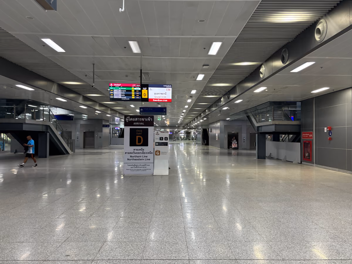 A wide, quiet station concourse with a polished floor and a sign for Gate D, arrivals from the Northern and Northeastern lines