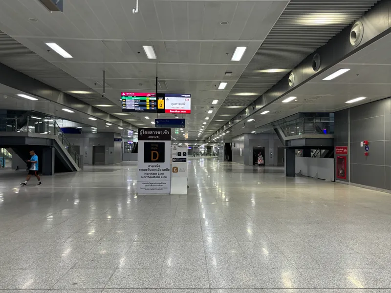 A wide, quiet station concourse with a polished floor and a sign for Gate D, arrivals from the Northern and Northeastern lines