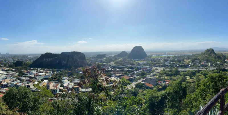 Steep green-topped limestone peaks of the Marble Mountains rising from low houses and trees, seen from a high point